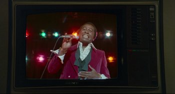 Movie still from “All That Jazz” (1979), directed by Bob Fosse – A man in a red jacket is singing on a television; Medium shot, Low angle