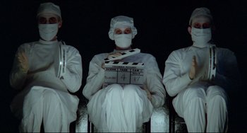 Movie still from “All That Jazz” (1979), directed by Bob Fosse – A group of people sitting in front of a movie screen; Medium shot, Low angle