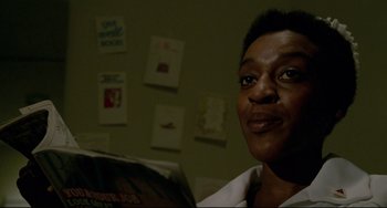 Movie still from “All That Jazz” (1979), directed by Bob Fosse – A woman sitting in front of a wall holding a magazine; Close Up shot, Low angle