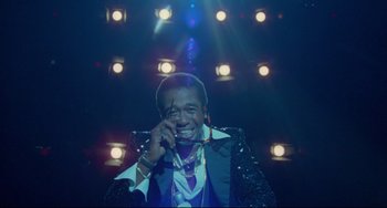 Movie still from “All That Jazz” (1979), directed by Bob Fosse – A man in a black jacket and a purple tie is talking on the phone; Medium shot, Low angle