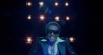 Movie still from “All That Jazz” (1979), directed by Bob Fosse – A man wearing a black jacket and sunglasses; Medium shot, Low angle