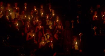Movie still from “All That Jazz” (1979), directed by Bob Fosse – A group of people sitting in a dark room holding lit candles; Wide shot, High angle