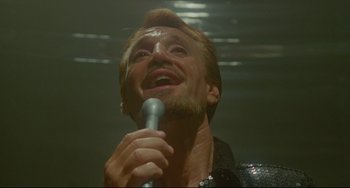 Movie still from “All That Jazz” (1979), directed by Bob Fosse – A man with a beard is holding a microphone; Close Up shot, Low angle
