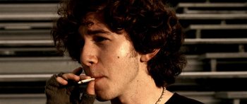 Movie still from “All the Boys Love Mandy Lane” (2006), directed by Jonathan Levine – A man with curly brown hair is smoking a cigarette; Extreme Close Up shot, High angle