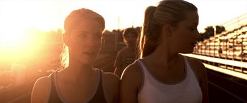 Movie still from “All the Boys Love Mandy Lane” (2006), directed by Jonathan Levine – Two young women standing next to each other in front of a group of people; Close Up shot, Over the shoulder angle