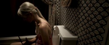 Movie still from “All the Boys Love Mandy Lane” (2006), directed by Jonathan Levine – A woman sitting on a toilet in front of a curtain; Medium shot, High angle