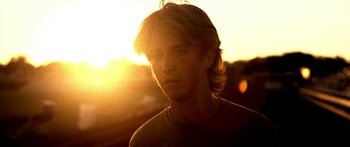 Movie still from “All the Boys Love Mandy Lane” (2006), directed by Jonathan Levine – A young man is standing in front of the setting sun; Close Up shot, Low angle