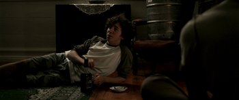 Movie still from “All the Boys Love Mandy Lane” (2006), directed by Jonathan Levine – A man sitting at a table with a bottle of beer; Medium shot, High angle