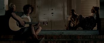 Movie still from “All the Boys Love Mandy Lane” (2006), directed by Jonathan Levine – Two people sitting on steps with a guitar in front of them; Wide shot, Low angle