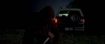 Movie still from “All the Boys Love Mandy Lane” (2006), directed by Jonathan Levine – A person with a knife in the dark near a car; Medium shot, Over the shoulder angle
