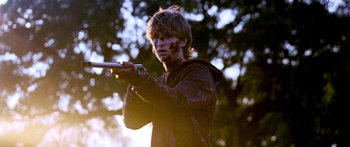 Movie still from “All the Boys Love Mandy Lane” (2006), directed by Jonathan Levine – A young man is holding a gun in the woods; Medium shot, Over the shoulder angle