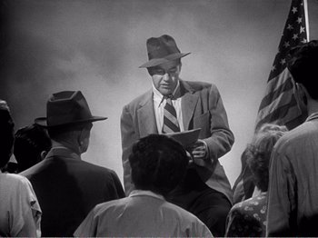 Movie still from “All the King's Men” (1949), directed by Robert Rossen – An old photo of a man in a suit and hat; Medium shot, Over the shoulder angle