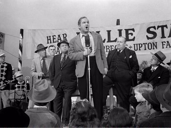 Movie still from “All the King's Men” (1949), directed by Robert Rossen – An old photo of a man singing on a microphone; Medium shot, Low angle