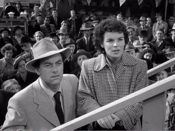 Movie still from “All the King's Men” (1949), directed by Robert Rossen – A man and a woman sitting next to each other in front of a crowd; Medium shot, High angle
