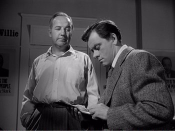 Movie still from “All the King's Men” (1949), directed by Robert Rossen – Two men are looking at a piece of paper together; Medium shot, Low angle