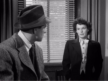 Movie still from “All the King's Men” (1949), directed by Robert Rossen – A man and a woman in a suit and tie talking to each other; Medium shot, Over the shoulder angle