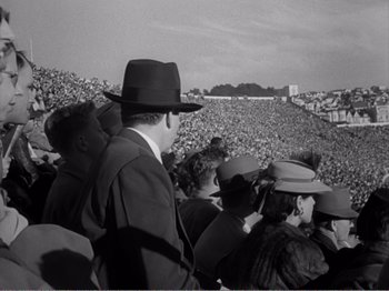 Movie still from “All the King's Men” (1949), directed by Robert Rossen – A group of people sitting in the stands at a sporting event; Wide shot, High angle