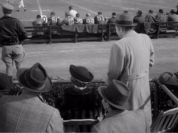 Movie still from “All the King's Men” (1949), directed by Robert Rossen – A black and white photo of a group of men sitting on a bench; Wide shot, High angle