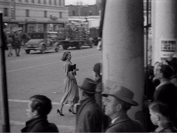 Movie still from “All the King's Men” (1949), directed by Robert Rossen – A woman walking down the street with a book in her hand; Wide shot, High angle