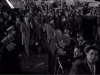 Movie still from “All the King's Men” (1949), directed by Robert Rossen – A crowd of people standing in the rain with umbrellas; Wide shot, High angle