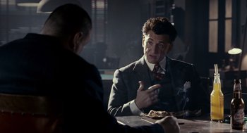 Movie still from “All the King's Men” (2006), directed by Steven Zaillian – A man sitting at a table with another man in front of him; Medium shot, Over the shoulder angle