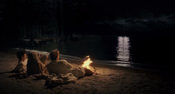 Movie still from “All the King's Men” (2006), directed by Steven Zaillian – Two people sitting on the beach by the water at night; Wide shot, High angle