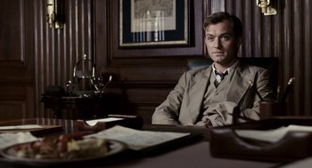 Movie still from “All the King's Men” (2006), directed by Steven Zaillian – A man sitting at a table in a suit; Medium shot, Low angle