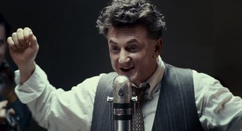 Movie still from “All the King's Men” (2006), directed by Steven Zaillian – A man in a vest and tie is talking into a microphone; Close Up shot, Low angle