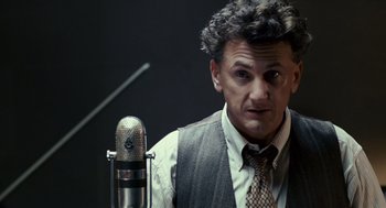 Movie still from “All the King's Men” (2006), directed by Steven Zaillian – A man in a vest and tie standing in front of a microphone; Close Up shot, High angle