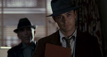 Movie still from “All the King's Men” (2006), directed by Steven Zaillian – A man wearing a hat and holding papers; Close Up shot, Over the shoulder angle