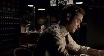 Movie still from “All the King's Men” (2006), directed by Steven Zaillian – A man sitting at a table in front of a laptop; Medium shot, High angle