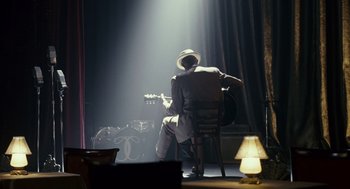 Movie still from “All the King's Men” (2006), directed by Steven Zaillian – A man sitting in a chair in a room with a lamp; Wide shot, Over the shoulder angle