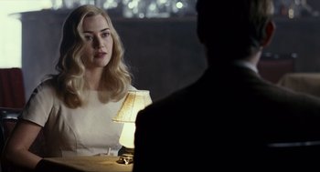 Movie still from “All the King's Men” (2006), directed by Steven Zaillian – A woman sitting at a table with a lamp in front of a man; Medium shot, Over the shoulder angle