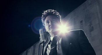 Movie still from “All the King's Men” (2006), directed by Steven Zaillian – A man in a suit and tie holding a microphone; Close Up shot, Low angle