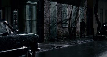 Movie still from “All the King's Men” (2006), directed by Steven Zaillian – A man standing on the side of the road near a building; Extreme Wide shot, High angle