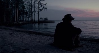 Movie still from “All the King's Men” (2006), directed by Steven Zaillian – A man sitting on the beach at night; Wide shot, Over the shoulder angle