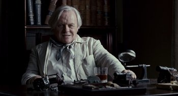 Movie still from “All the King's Men” (2006), directed by Steven Zaillian – An older man sitting at a table with a glass of wine; Medium shot, Low angle