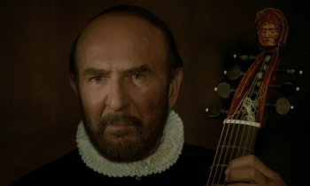 Movie still from “Tous les matins du monde” (1991), directed by Alain Corneau – A man with a beard wearing a black shirt and holding a guitar; Close Up shot, Over the shoulder angle