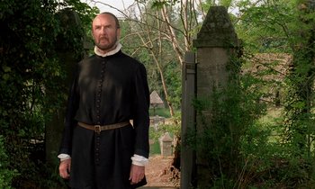 Movie still from “Tous les matins du monde” (1991), directed by Alain Corneau – A man dressed in black standing in front of a grave yard; Medium shot, Low angle