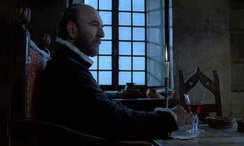 Movie still from “Tous les matins du monde” (1991), directed by Alain Corneau – A man sitting at a table with a glass of red wine; Medium shot, Low angle