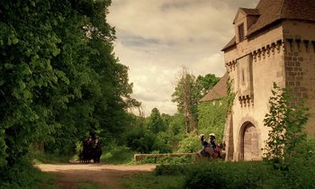 Movie still from “Tous les matins du monde” (1991), directed by Alain Corneau – A group of people sitting on a bench near a building; Extreme Wide shot, Low angle