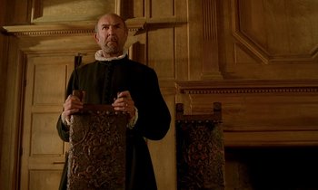 Movie still from “Tous les matins du monde” (1991), directed by Alain Corneau – A man in a black coat holding a brown bag; Medium shot, Low angle