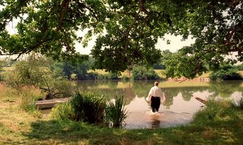 Movie still from “Tous les matins du monde” (1991), directed by Alain Corneau – A man standing in the water near a body of water; Extreme Wide shot, High angle