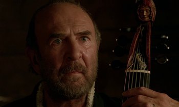 Movie still from “Tous les matins du monde” (1991), directed by Alain Corneau – An older man with a beard holding a guitar; Close Up shot, Low angle