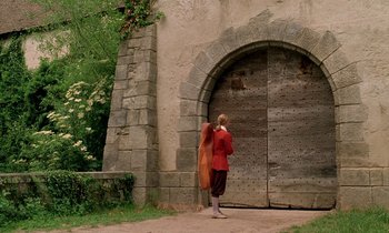 Movie still from “Tous les matins du monde” (1991), directed by Alain Corneau – A woman in a red jacket standing in front of a stone building; Wide shot, Low angle