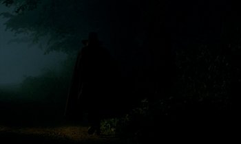 Movie still from “Tous les matins du monde” (1991), directed by Alain Corneau – A man in a black cape standing in the dark; Wide shot, Low angle
