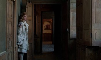 Movie still from “Tous les matins du monde” (1991), directed by Alain Corneau – A woman dressed in period clothing standing in a doorway; Medium shot, Low angle