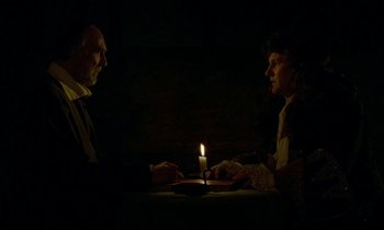 Movie still from “Tous les matins du monde” (1991), directed by Alain Corneau – Two people sitting in front of a candle in a dimly - lit room; Medium shot, Over the shoulder angle