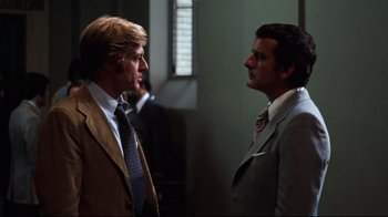 Movie still from “All the President's Men” (1976), directed by Alan J. Pakula – Two men in business suits talking to each other; Medium shot, Low angle