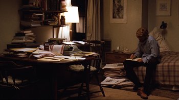 Movie still from “All the President's Men” (1976), directed by Alan J. Pakula – A man sitting at a table in front of papers; Wide shot, High angle